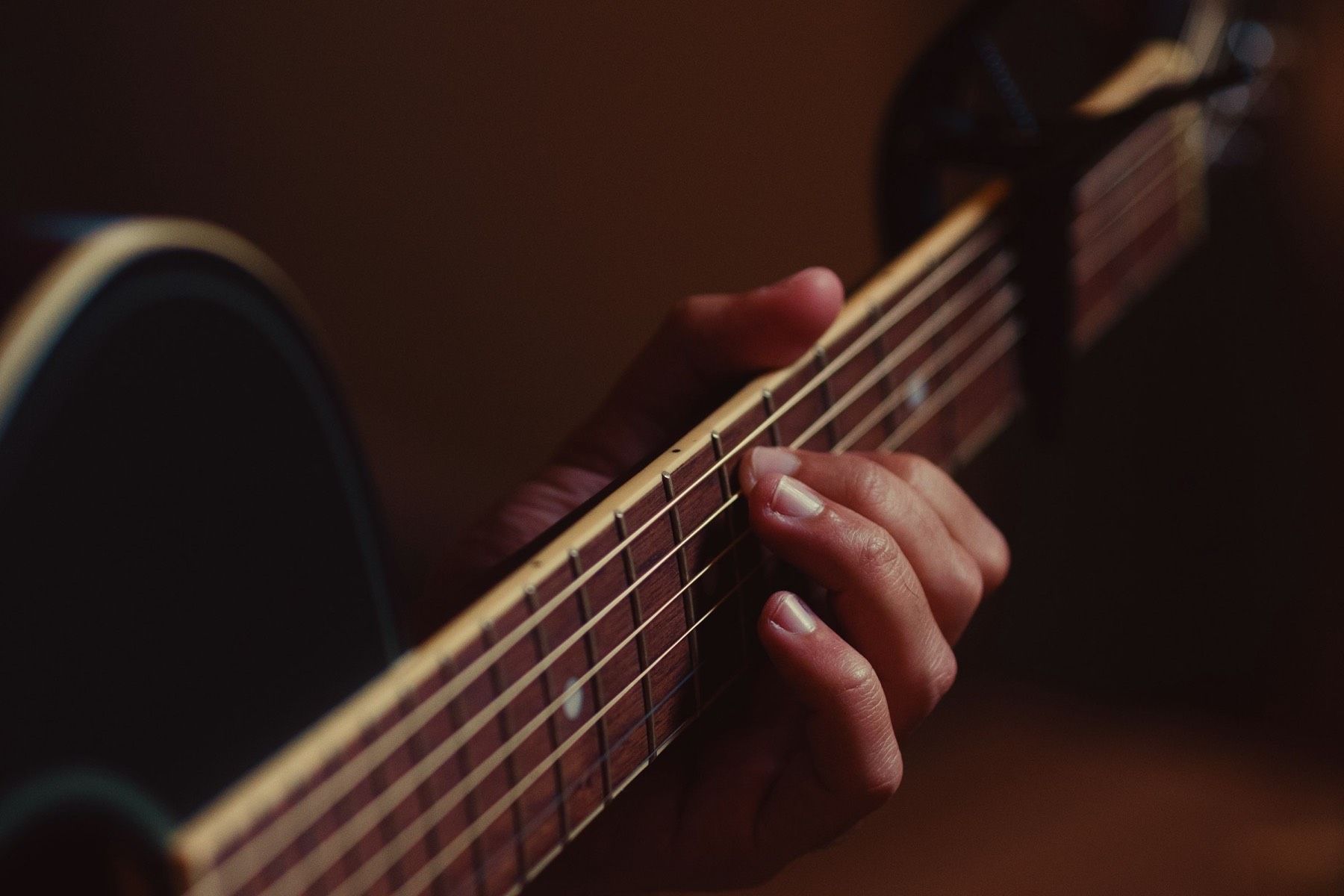 Nahaufnahme einer Hand, die einen Akkord auf dem Griffbrett einer Gitarre greift